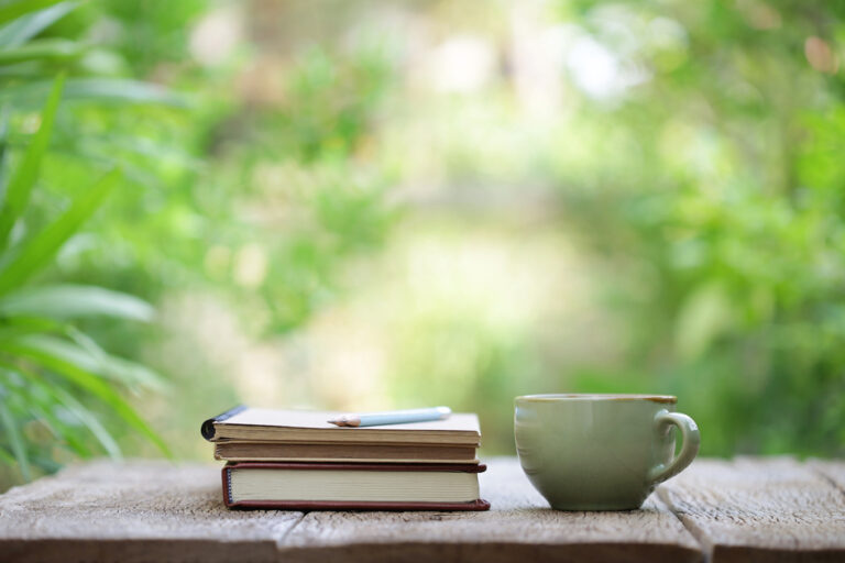 Closed Notebook with pencil and cup on wooden table