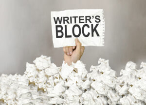 male hand with sign writers block coming out of used scrunched up paper on floor