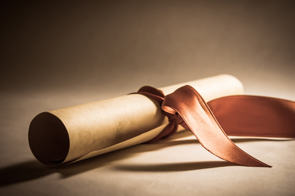 A parchment scroll, rolled up with red ribbon laid at an oblique angle. Processed to give a vintage or retro appearance.