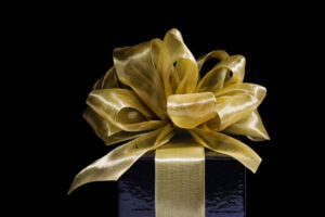 Christmas Gift Wrapped in Gold Ribbons, Bows on Black Background