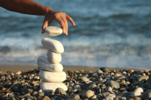 female hand making stone pile on beach